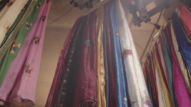  Many different colourful cloths hanging form a pole on a indian textile market