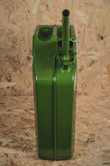 Front view of new green metal jerry can or gas container standing on a wooden surface and...