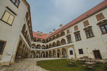 Fototapeta na wymiar Beautiful courtyard with arches of the Ptuj castle. Facade and main square of Ptujski grad on a dull autumn day.