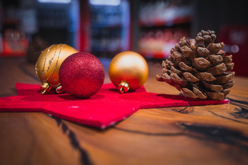 Beautiful christmas tree ornaments in red and gold color on a wooden table. Red bar environment in the background.