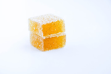 Pineapple, lemon, vanilla pate de fruit (jelly, marmalade, fruit candy) covered with sugar. White background, back view. There is a sliced jelly on a photo to show a texture inside of pate de fruit.