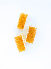 Pineapple, lemon, vanilla pate de fruit (jelly, marmalade, fruit candy) covered with sugar. White background, top view. There is a sliced jelly on a photo to show a texture inside of pate de fruit.