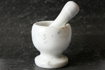 Stupa - a tool for crushing and grinding. White dishes on a dark background