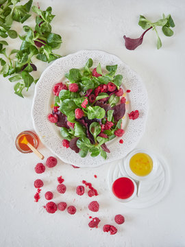 From above bright composition of tasty appetizing salad with ripe raspberry green spinach and aromatic sauce on white background
