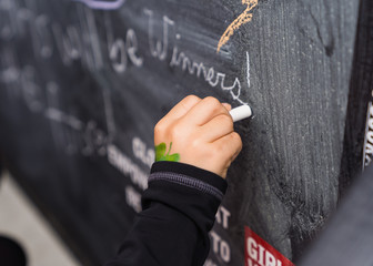Writing messages on black chalkboard with chalk 