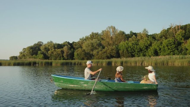 Family holidays on the water. People sails in a green wooden boat over the lake, slow-motion video