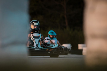 Two men are racing in commercial amateur gokart race on a closed circuit. Fun leisure racing activity, go kart trophy between friends. - obrazy, fototapety, plakaty