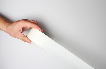 hand and Scotch tape on a gray background