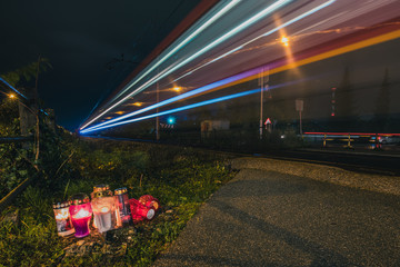 Group of candles standing next to a pedestrian train grade crossing where a fatalaty has happened...