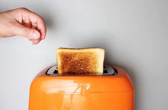 hand toast and orange toaster on a light background