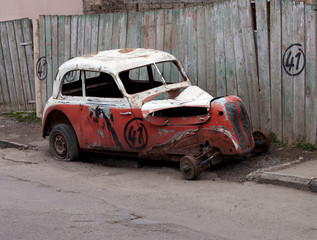 Broken vintage car on dirty roadside