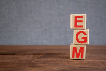 EGM (extraordinary general meeting) acronym on wooden cubes on dark wooden backround. Business concept.