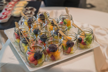 An assortiment of dessert fruit on a white plate at a banquet or a party. Catering with fruit in glass jars.