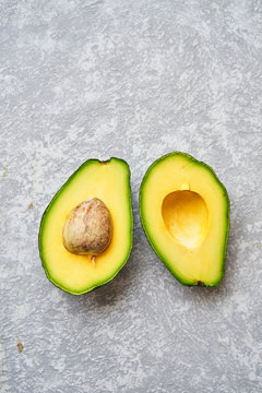 Top view of fresh ripe avocado cut in half on light grey texture background