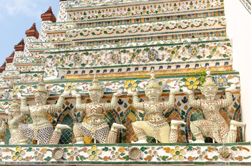 Ancient guardians at the temple of Wat Arun in Bangkok, Thailand, with a gate on the background