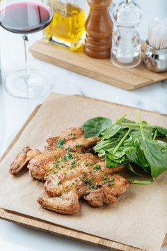 From above of fried golden chicken and herbs on wooden board with basil leaves in restaurant