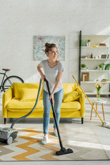 happy young woman cleaning carpet with vacuum cleaner