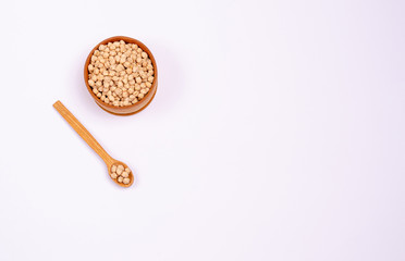 Dry chickpeas for vegans in a wooden spoon and bowl on a white background, copy space, place for text