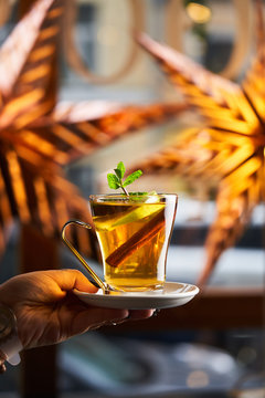Crop hand with hot cocktail in glass decorated with slice of lemon anise and cinnamon 