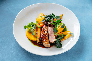 From above tasty roasted meat served with pieces of mango and pumpkin on plate in restaurant