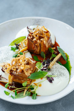 Closeup pieces of roasted meat with truffles and fresh herbs served on plate in cafe