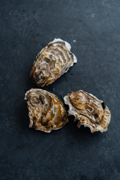 From above closed uncooked clams placed on black table surface in restaurant