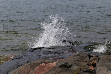 Waves hitting rocks in Helsinki, Finland. Beautiful photo representing the power and strength of the sea during windy weather. Waves can be dangerous but they also create beautiful splashes.
