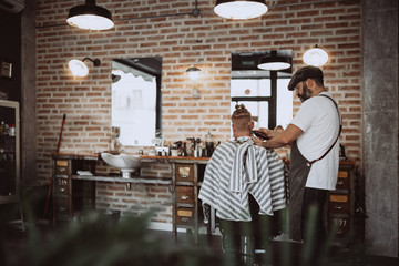 Back view of unrecognizable redhead man in modern hairdresser barber cutting his hair