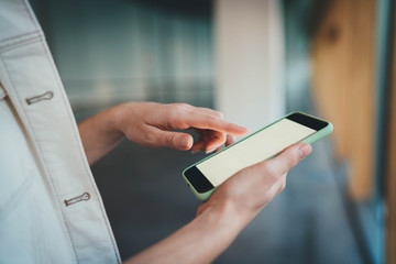 Side view of female hands using cellphone device indoor with blank screen, Businesswoman Using Smartphone Typing Text on touch Screen Browsing Internet Online Communication, Mock Up of Mobile Phone