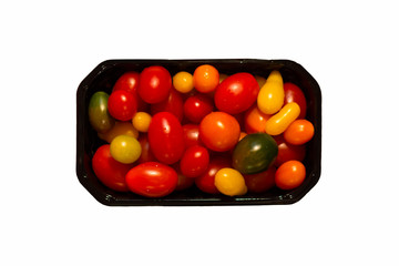 many multicolored cherry tomatoes in a black plastic box isolated on white background, top view, use as an advertisement of green grocery