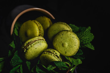 Homemade green macarons green with mint on dark background. Dark food.