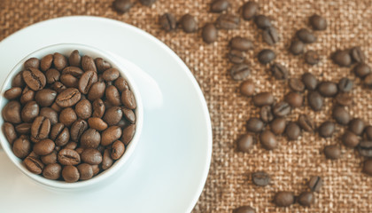 Cup of coffee beans. Coffee beans scattered around