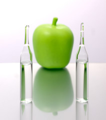 medical ampoules with an apple on a white background. Natural remedies.