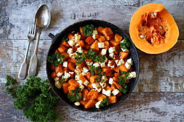 Baked slices of pumpkin with slices of white cheese. Warm salad with pumpkin and feta cheese. Vegetarian food. Healthy eating