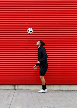 Man playing soccer ball on street