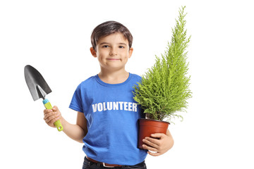 Boy volunteer holding a plant and a spade