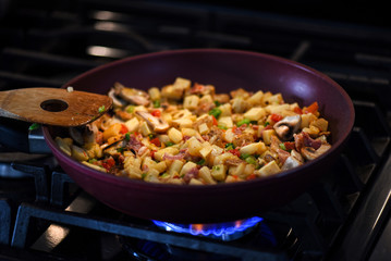 Breakfast hash mix in frying pan with wooden spatula on stove