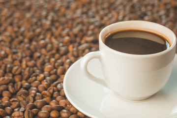 A Cup of coffee stands on coffee beans