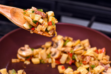 Breakfast hash on wooden spatula with frying pan in background