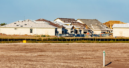New homes under construction are seen across an open field, also destined for new homes