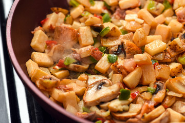 Breakfast hash steaming in frying pan on stove closeup macro