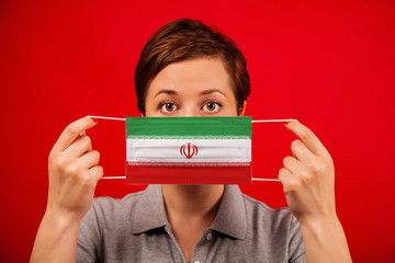 Coronavirus COVID-19 in Iran. Woman in medical protective mask with the image of the flag of Iran.
