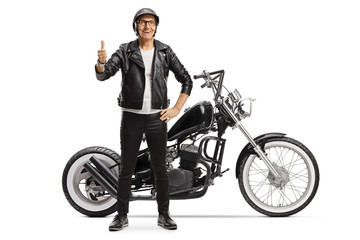 Obraz na płótnie Canvas Elderly male biker standing next to a chopper motorbike and showing thumbs up