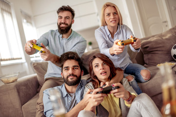 Smiling friends playing video games at home