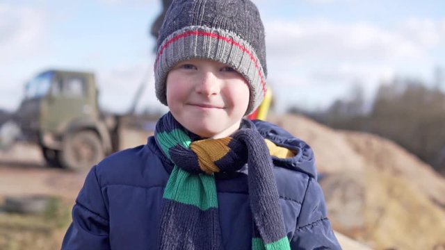 A close-up of a beautiful boy on a walk through the village in the spring. Tempering with a walk in the fresh air