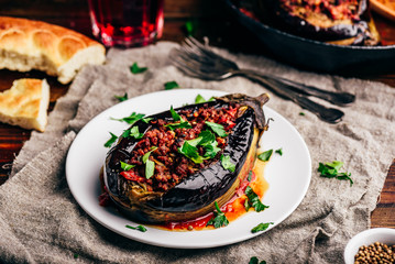 Baked eggplant stuffed with ground beef, tomatoes and spices on white plate. Traditional dish...