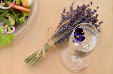 a glass with a flower and a bouquet of lavender and salad