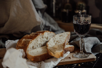Flat-lay of freshly baked sourdough bread loaf and bread slices on rustic wooden board over grey concrete table 