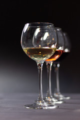 Row of white, pink, red wine in glasses on black background