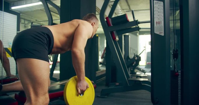 man Athlete bent-over dumpbell rows exercise in gym hard working